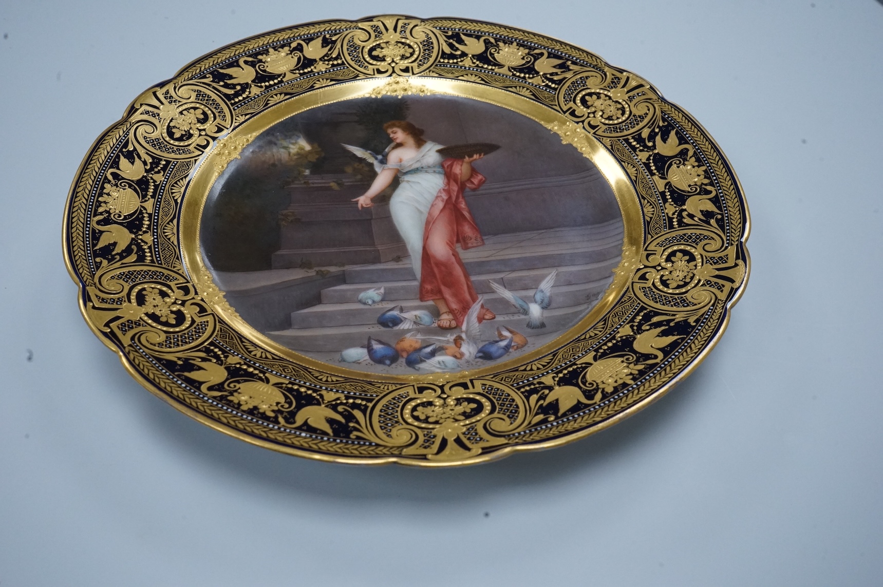 A Vienna-style cabinet plate, painted with a Vestal Virgin, after P. Wagner, depicting a lady feeding pigeons, signed Goget?, 24cm in diameter
